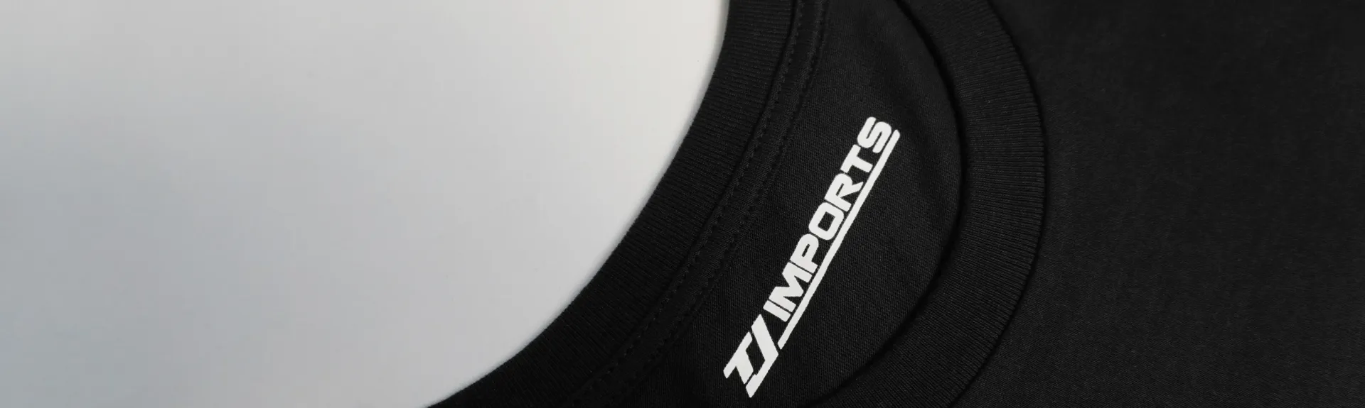 Ein hochwertiges Textilfinishing: Ein Druck innen im Nackenbereich eines schwarzen Merch T-Shirts