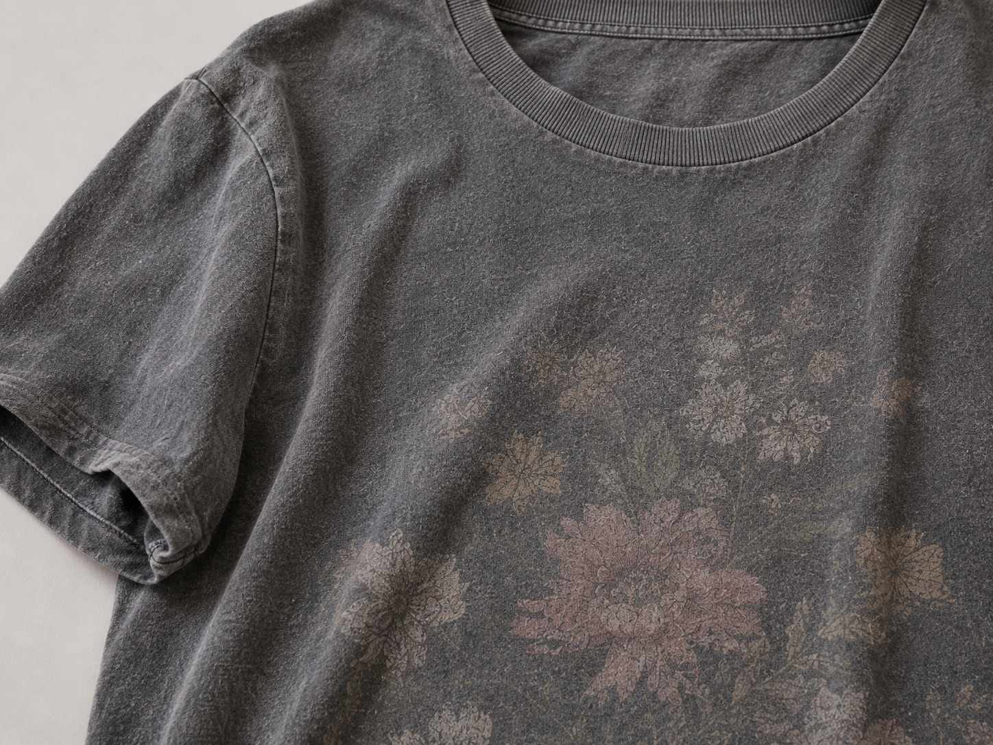 Ein graues T-Shirt mit einem floralem Print, das nach häugigem Waschen schon deutlich ausgeblichen ist und der Print ist nicht mehr gut erkennbar.
